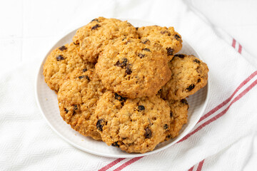 Homemade oatmeal cookies with raisins in a white plate on a light background closeup	