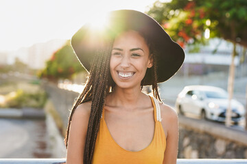 Happy young multiracial woman smiling in the city with sunset in background