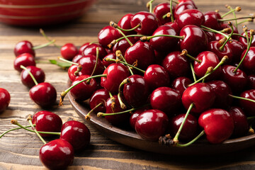 Ripe cherries in wooden plate on the wooden table View from above a rustic style image