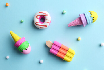 Toy ice creams, donut and beads on light blue background, flat lay