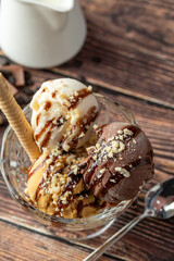 Chocolate, cream and caramel Roma ice cream in a glass bowl with hazelnut and chocolate sauce poured over it.
