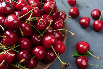 Red cherries in transparent wooden bowl on gray blurred background Fresh berries at summer