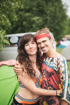Two bohemian friends hugging smiling wearing funky clothes at festival