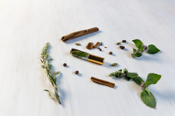 bottle with organic perfume made of herbs and spices on white wooden background