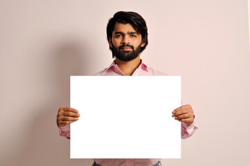 Smart casual Indian man holding empty sign board and serious look
