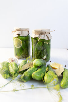 Cooking preserve in Glass jar with fermented cucumbers with lemon, herbs, spices on white background