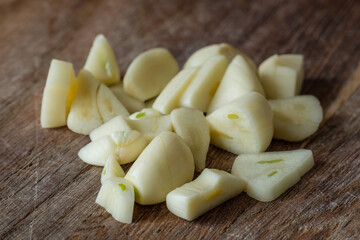 Zubereitung von Knoblauch / Knoblauchzehen als Zutat beim Kochen auf einem Holzbrettchen