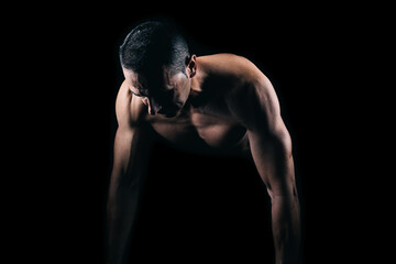 Muscular man doing push-ups with black background