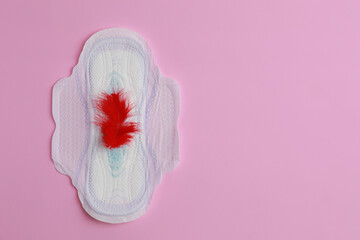 Menstrual pad and feather on pink background, top view. Space for text
