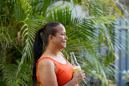 upper body of female holding a stubby of beer