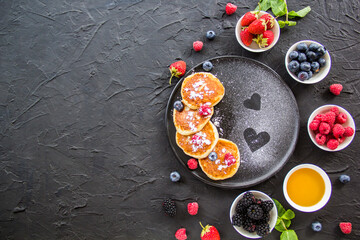 A healthy breakfast of cheese pancakes, berries, and honey. Creative atmospheric decoration