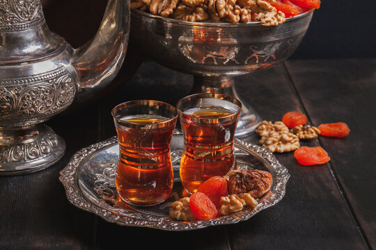 Plate with tea in armuda glasses, vintage jug, a vase with dried fruit - Ancient East metallic crockery