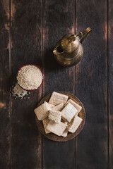 Pieces of tahini halva, sesame seeds in a bowl, an vintage jug.