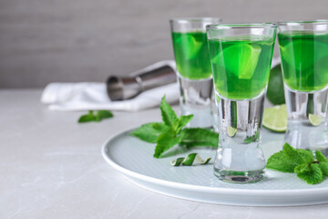 Delicious mint liqueur with lime and green leaves on white table. Space for text