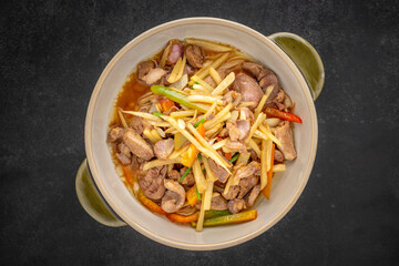 Kruang Nai Gai Pad King, Thai food, stir fried chicken offal, variety meats, pluck or organ meats with ginger in ceramic bowl on dark tone texture background, top view