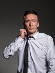 Young business man in shirt and tie looking at camera. Portrait businessman on a dark background with copy space.