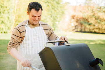 Man smiles and is happy while barbecuing in the garden. Man prepares the grill in the garden.