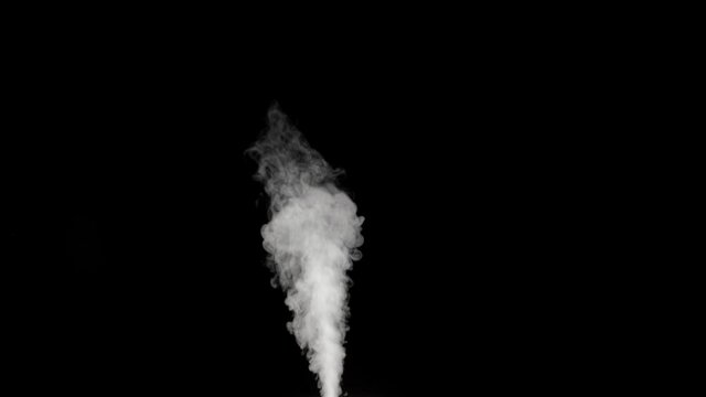 White real clouds of steam humidifier in the air on black background isolated in slowmo. Beautiful smoke.