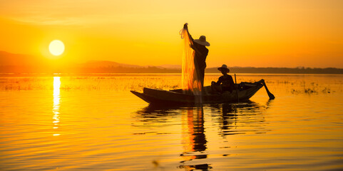 Naklejka na ściany i meble The Fishermen cast their nets into the water during sunset in Thailand.
