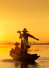 The Fishermen cast their nets into the water during sunset in Thailand.