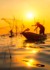 The Fishermen cast their nets into the water during sunset in Thailand.