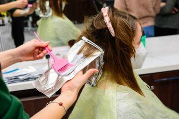 Hair coloring during the quarantine period, client and hairdresser in masks, hair bleaching.