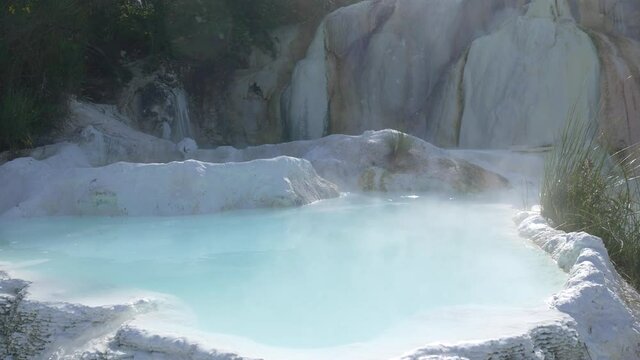 Geothermal pool and hot spring in Tuscany, Italy. Bagni San Filippo natural thermal waterfall in the morning with no people. The White Whale amidst forest.