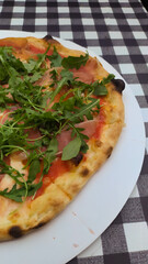 Prosciuto e arugula pizza on black and white squares background