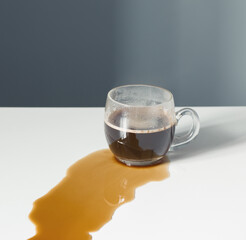 cracked cup with black coffee spilled on  white table