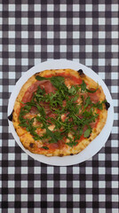 Prosciuto e arugula pizza on black and white squares background
