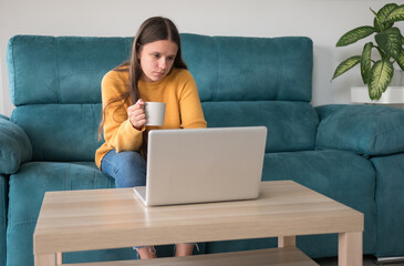 girl with laptop and cup of coffee on the sofa