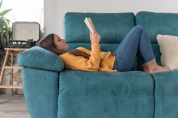 girl lying on the sofa reading a book