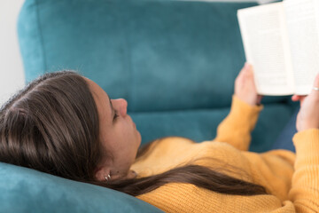 girl lying on the sofa reading a book