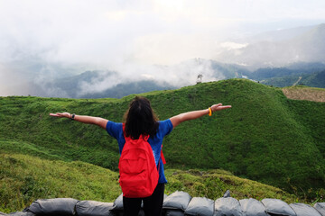 Asian woman is open hands for Destination and paradise of golden sunrise and sunset shining to the mist and fog in the jungle on the valley mountain. Aerial view the tropical rainforest in Thailand.