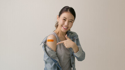 Young attractive beautiful asia female or teenage receive covid-19 anti virus vaccine in campaign vaccination safe life happy smile cheerful with blue, yellow, pink bandage on arm with copy space.