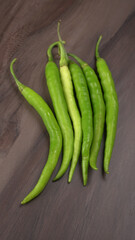 Fresh long Indian green chillies on wooden background.
