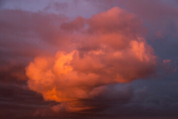 Epic sunset storm sky. Big white grey cumulus thunderstorm clouds in pink red orange sunlight background texture	