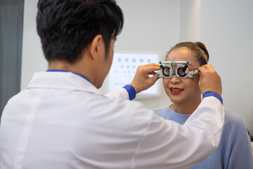 Selective focus at Optometrist face. While doctor using penlight and subjective refraction to  examine eye visual system of elder patient women with professional machine before made glasses.