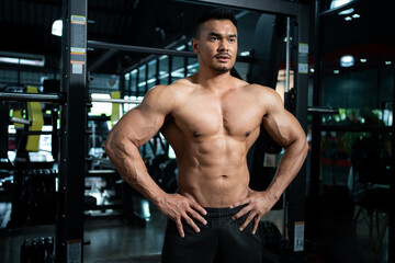 Fototapeta na wymiar Handsome shirtless adult Asian men sweating while lift up the barbell workout machine for muscle part inside of fitness gym. Bodybuilding athlete sport training for body strength and good health.