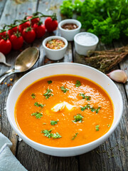 Cream tomato soup with fresh parsley on wooden table
