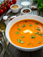 Cream tomato soup with fresh parsley on wooden table
