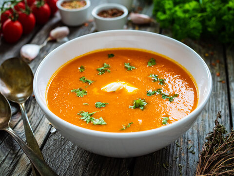 Cream tomato soup with fresh parsley on wooden table
