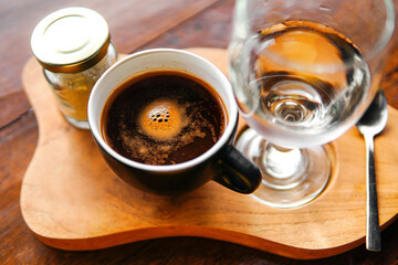 A cup of coffee, a glass of water and a bottle of sugar     