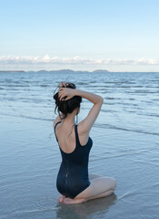 Back view of the young woman in a bathing suit on the beach