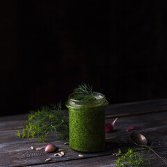 Homemade dill pesto sauce with seeds on wooden background, selective focus, space	