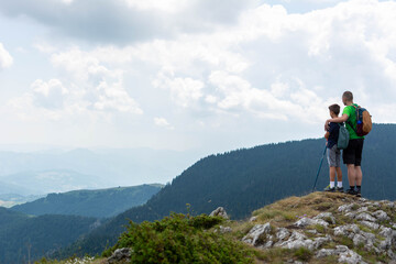 father and son hiking in scenic mountains. The father shows his son the sights. People having fun on the field. Concept of friendly family and of summer vacation.