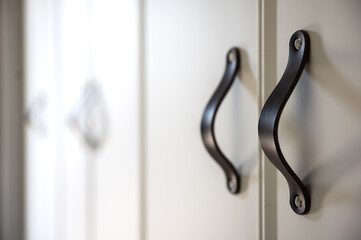 Close-up of black knobs on a white cabinet.