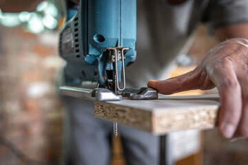 Close-up process of cutting wood board with jigsaw.