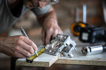 Carpenter at work, measuring wood for drilling.