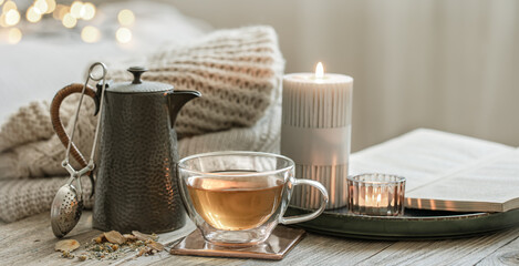 Cozy composition with a cup of tea and a teapot on a blurred background.